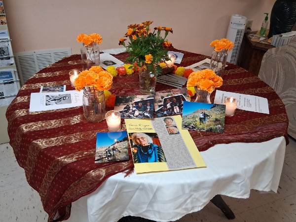 Día de los Muertos altar with burgundy tablecloth and mementos of loved ones.